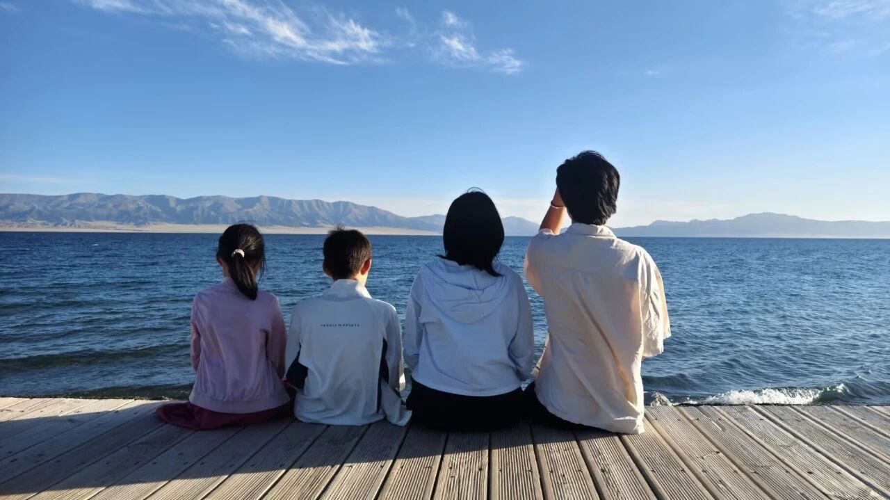 四个孩子坐在赛里木湖边